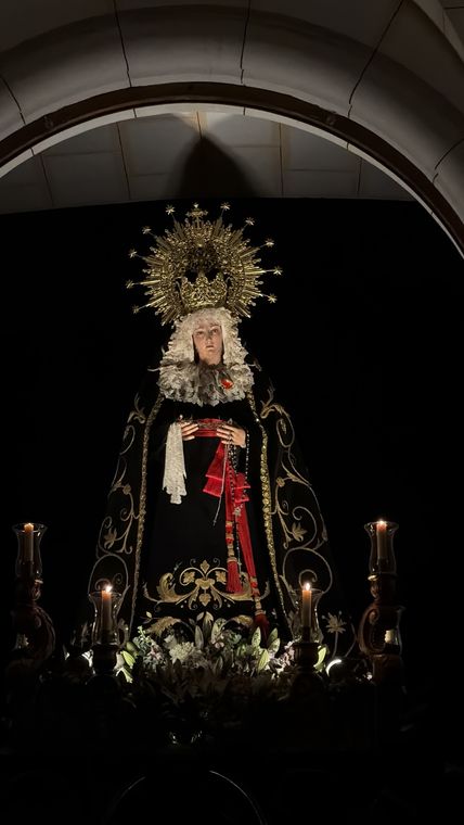 La Virgen de la Soledad bajo el arco del templo, alumbrada por candelabros
