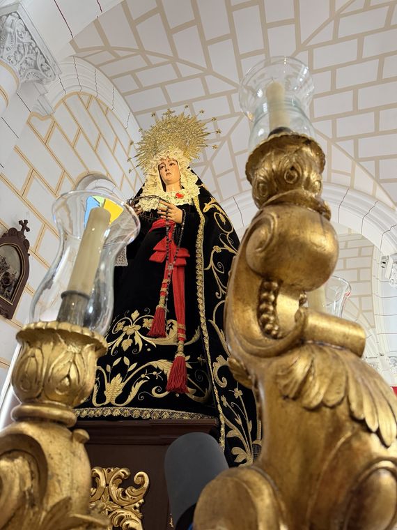 La Virgen de la Soledad vista desde abajo en su capilla, entre dos grandes candelabros dorados
