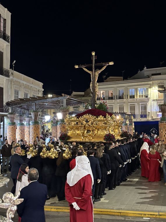 Los portadores bajo el trono del Cristo de la Paz, en dos filas, avanzando por la plaza