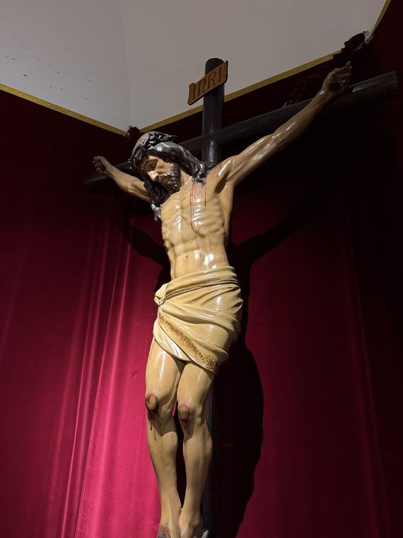 El Santísimo Cristo de la Paz visto desde abajo, crucificado sobre cortinaje granate