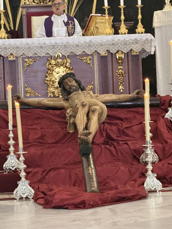 El Santísimo Cristo de la Paz tendido sobre terciopelo rojo ante el altar, entre candelabros de plata
