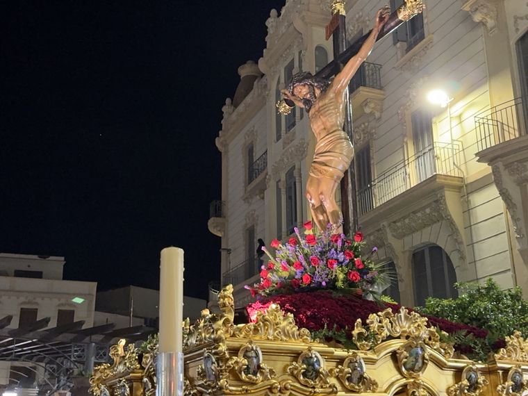 El Cristo de la Paz sobre el gran trono dorado, de noche, con las flores rojas del monte