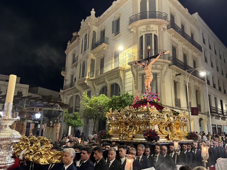 El Cristo de la Paz sobre su trono dorado, de noche, doblando la esquina de un edificio modernista