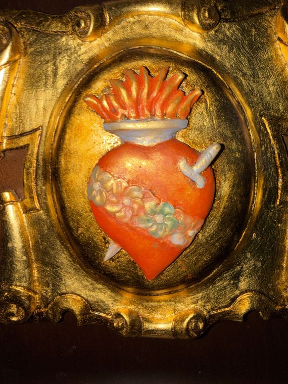 El escudo de la cofradía tallado en madera y dorado: corazón en llamas traspasado por un puñal y ceñido de rosas