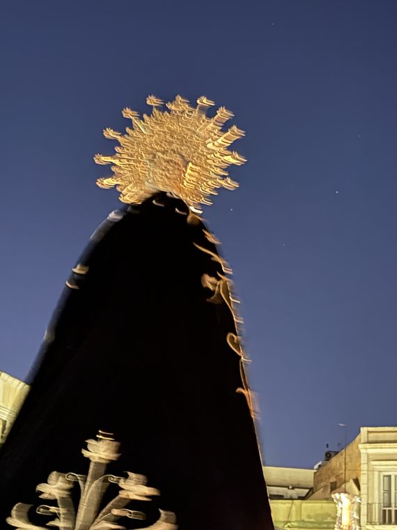 La corona y el manto de la Virgen recortados contra el cielo azul del anochecer