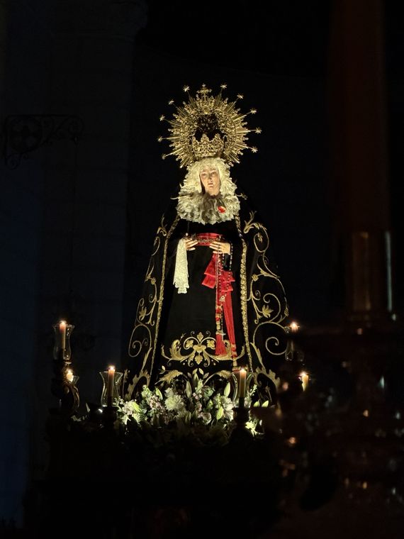 La Virgen de la Soledad iluminada por las velas en la penumbra de la parroquia