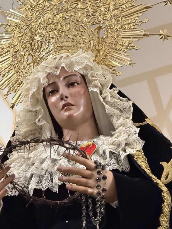 Primer primerísimo plano del rostro de Nuestra Señora de la Soledad, con lágrimas, tocado de encaje y corona de oro